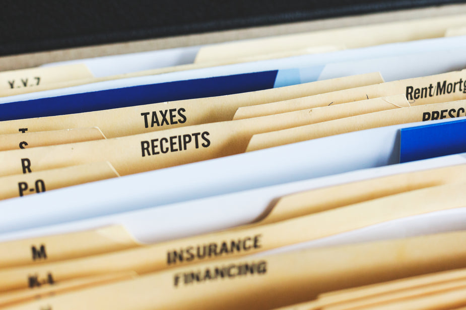 A close up of an open concertina file with spaces for taxes, receipts, insurance, and financing.